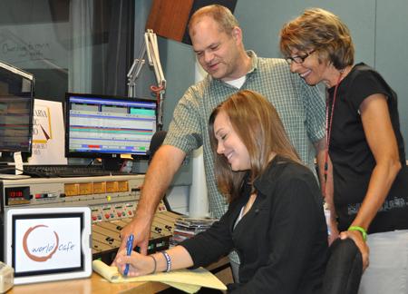 Salisbury University senior communication arts major and Delmarva Public Radio (DPR) membership assistant Michele Malinger checks notes on the new programming schedule with DPR producer Chris Ranck and membership director Angela Byrd.