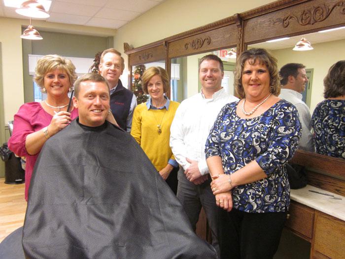 Hometown Heroes Barbershop stylist and manager Connie Kimbles Dill (far left) is pictured giving co-owner Gary Smith a trim. Looking on are (left to right) State Farm agent Richard Phillips, shop co-owner Lisa Smith, State Farm agent Frank Divilio and Compass Regional Hospice Development Officer Kenda Leager.