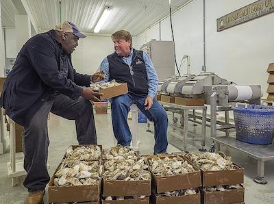 Carnelious Jones, known as C. J., talks oysters with Johnny Shockley. The Baltimore businessman said he has never known anyone who promoted the oyster industry like Shockley has. (Dave Harp)